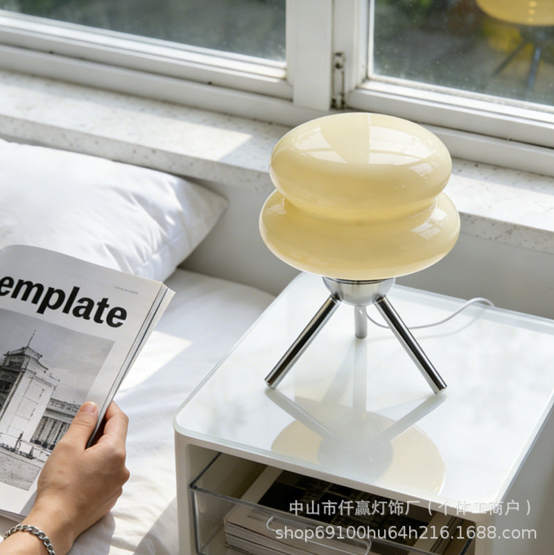 Ripple Glass Tripod Table Lamp in Cream beside a bed