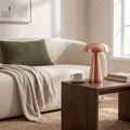 Copper cordless mushroom lamp on a walnut side table beside a cream sofa with olive cushions