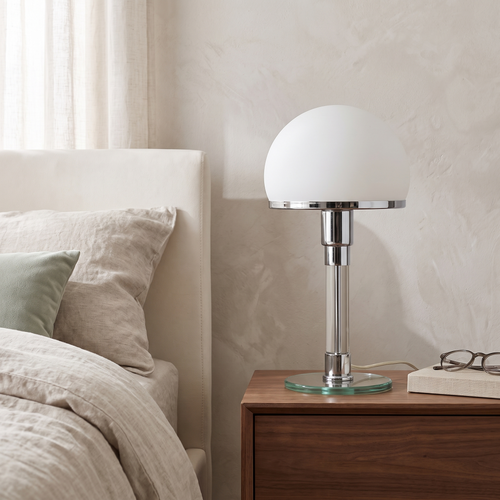 Opal glass dome table lamp beside a linen bed