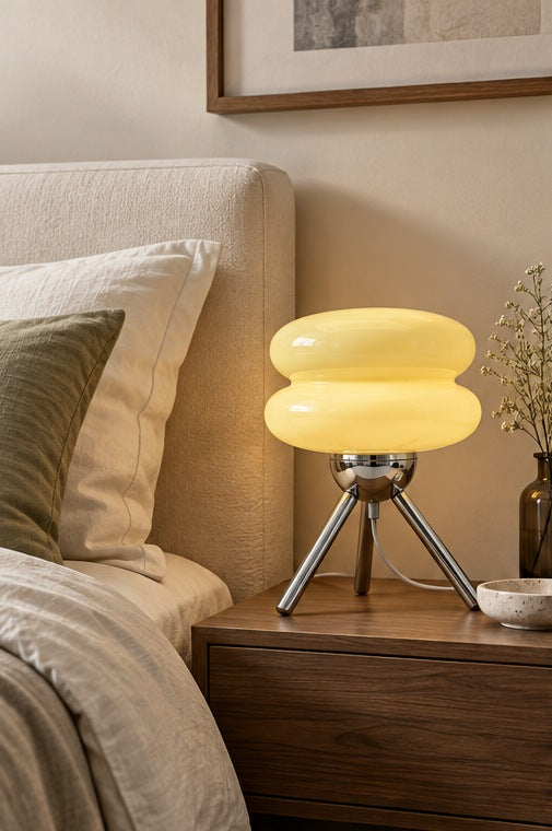Cream-yellow Ripple Glass Tripod Table Lamp with three chrome legs on a walnut bedside table